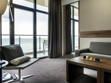 Панорамные окна в номере отеля с раздельной спальной зоной и гостиной.
