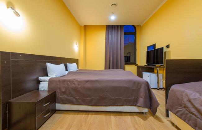 Светлый номер с желтыми стенами и мебелью в коричневых тонах.
