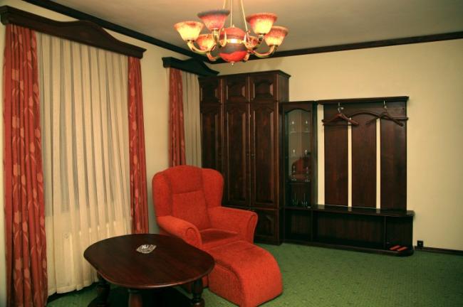 Гостиная номера в винтажном стиле с красным креслом и мебелью из темного дерева.