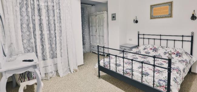 Двуспальная кованая кровать в светлом номере в стиле шебби-шик.