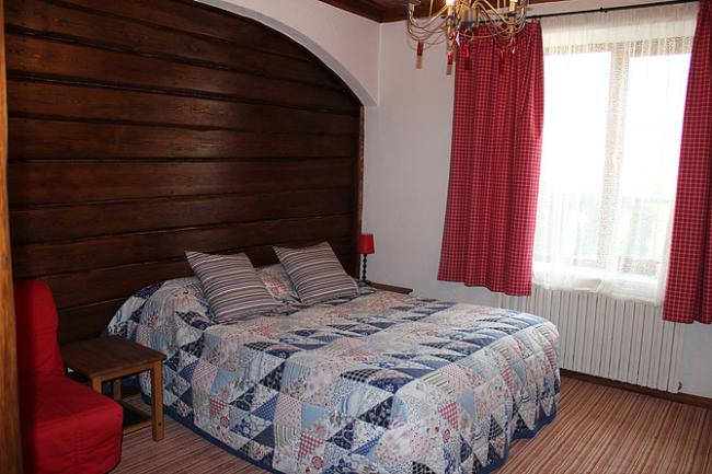 Двуспальная кровать с лоскутным покрывалом с номере в деревенском стиле.