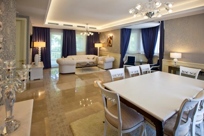 Гостевая комната в золотой вилле с диваном, креслами и обеденным столом.