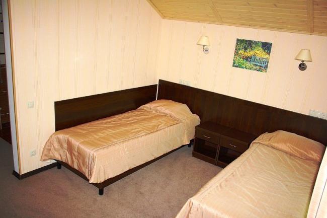Две односпальные кровати с большой тумбочкой в номере.