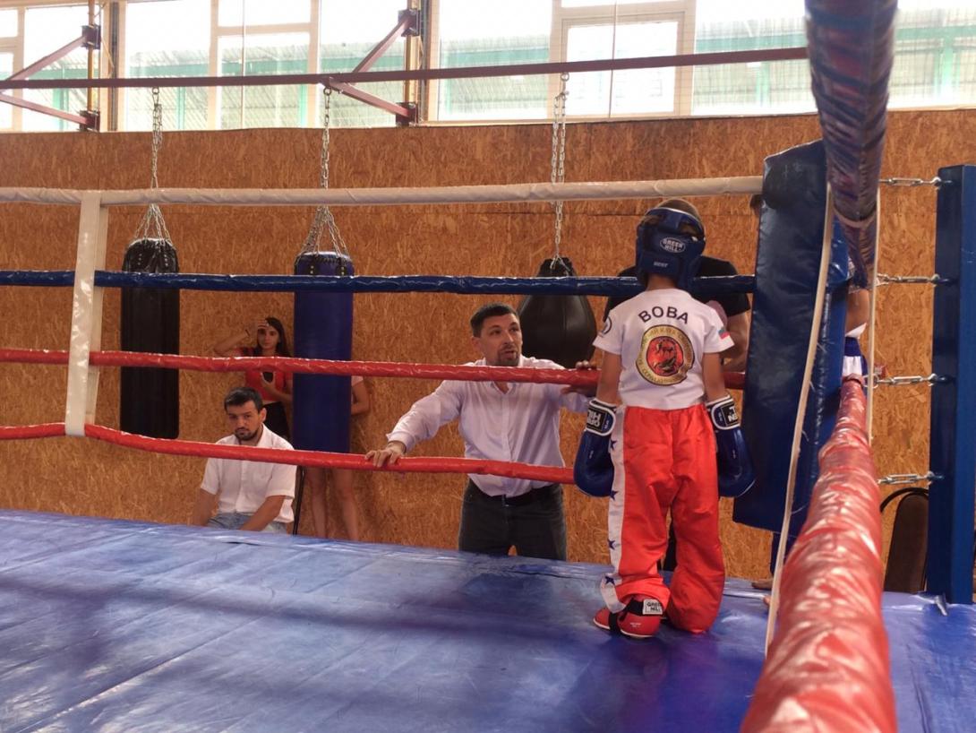 Тренер наставляет юного боксера на ринге.